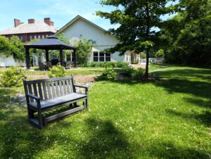 Photo of an outdoor space on a sunny day with a bench in front of a gazeebo