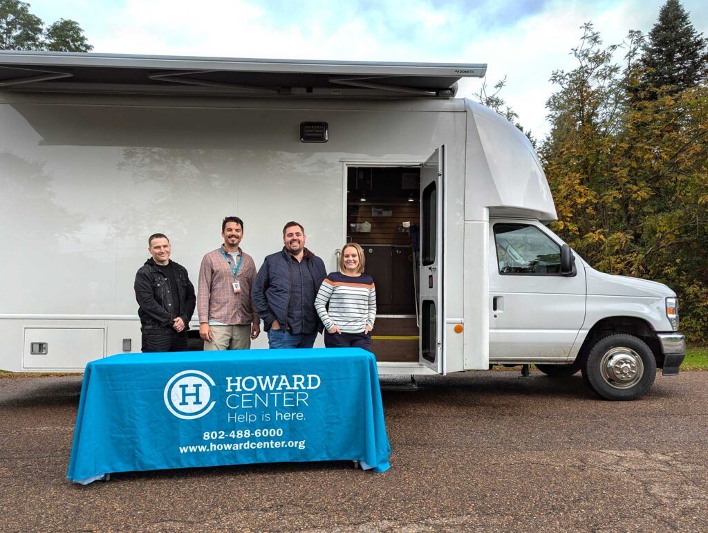 Four staff stand in front of an RV converted into a mobile substance use treatment clinic.