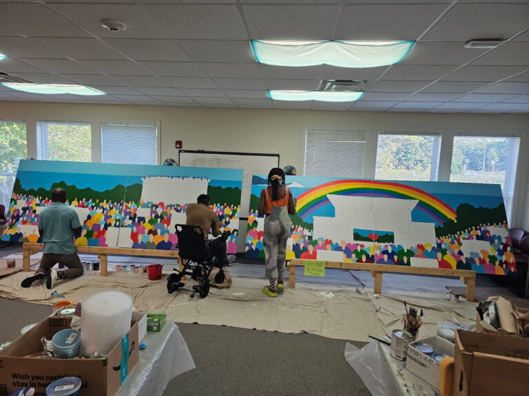 Artists work on the community mural in late June 2025
